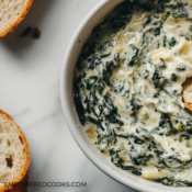 dipping bread in spinach artichoke dip