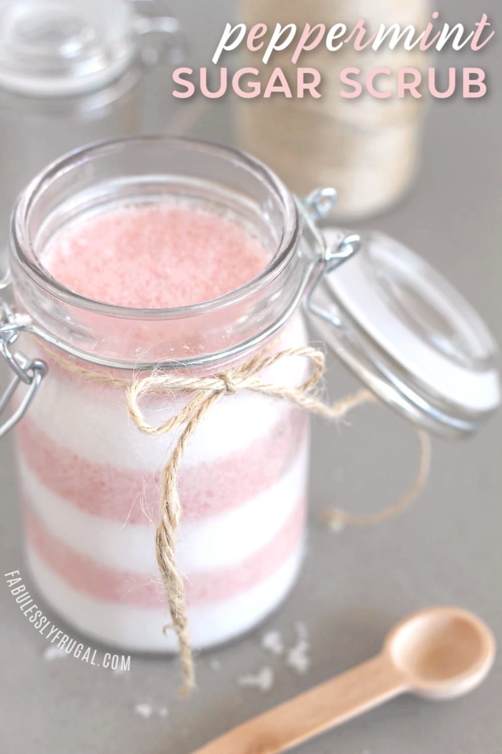 Layered candy cane sugar scrub in jar with twine and wooden spoon