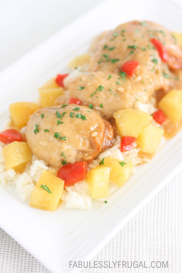 Plated Hawaiian chicken over rice with parsley garnish on a white plate– fabulesslyfrugal.com branding