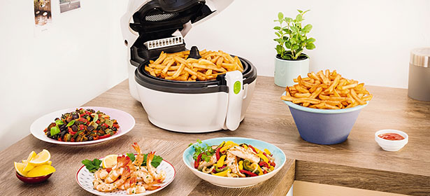 Air fryer with fries in it next to dishes of food