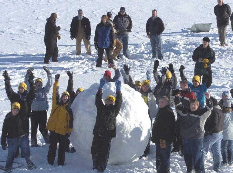 Group of people cheering next to massive snowball