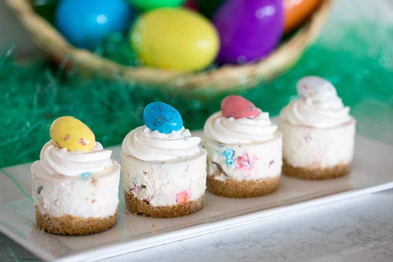 4 colorful mini cheesecakes with eggs on top