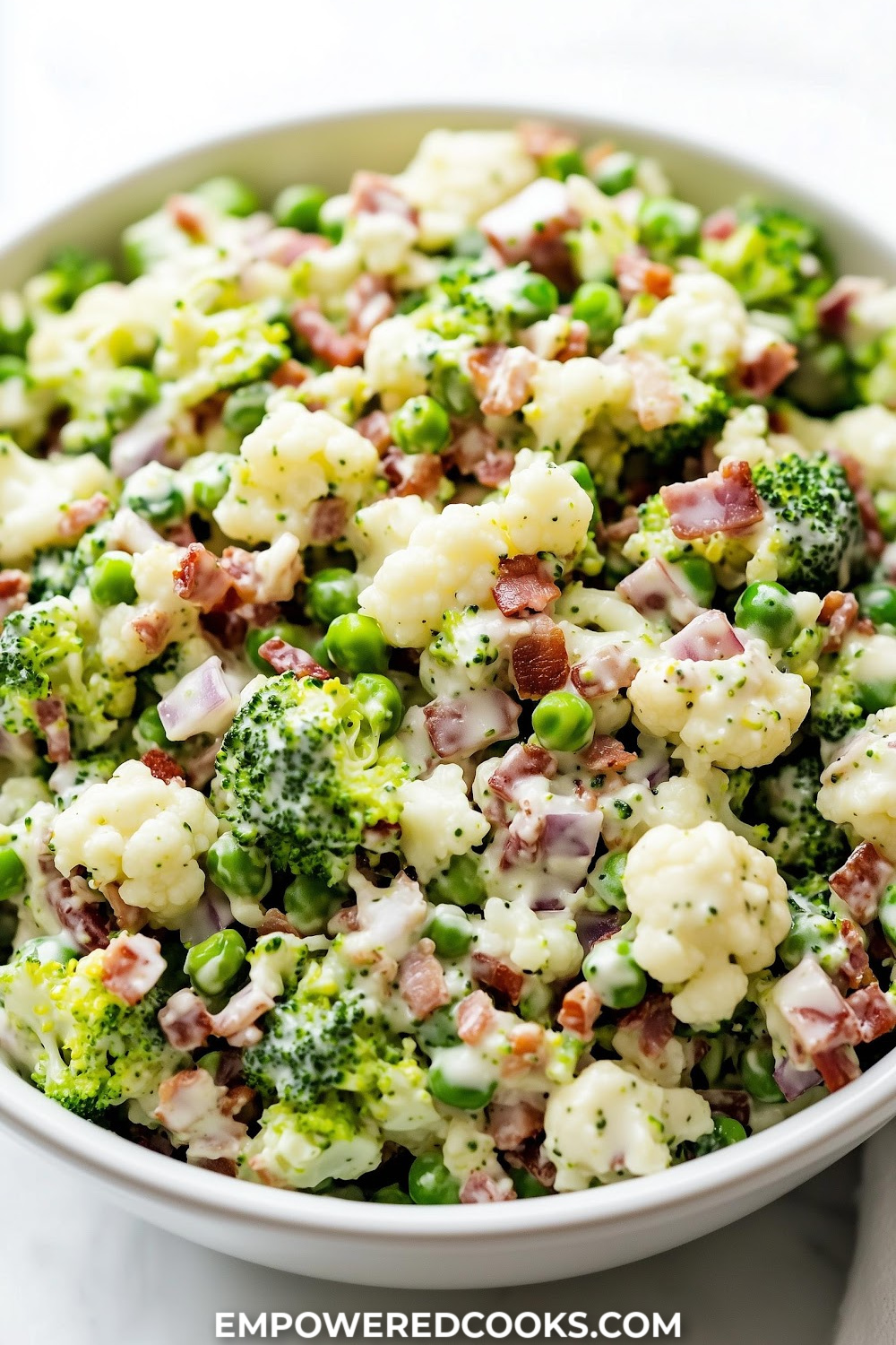 a large bowl of broccoli pea onion celery and bacon salad