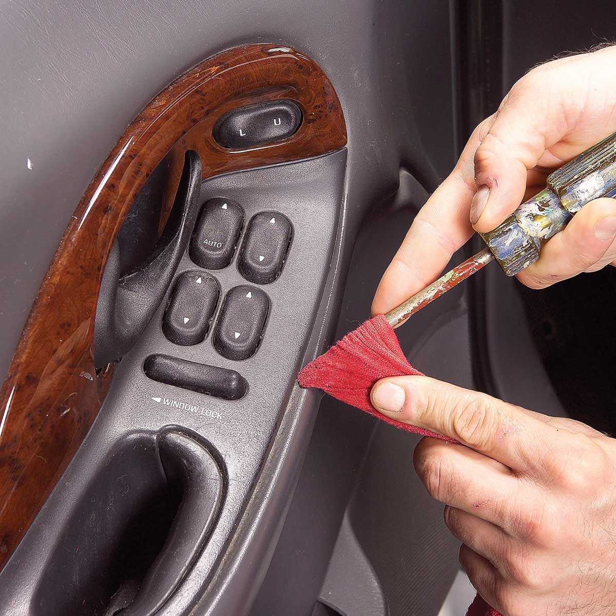 Cleaning car crevices with screwdriver and cloth