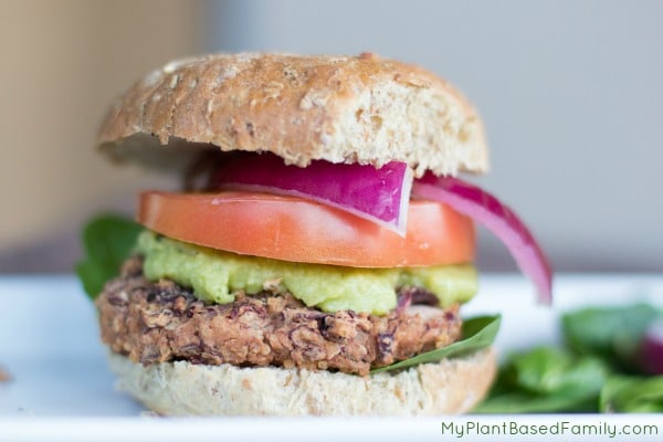 Vegan burger stacked with guacamole, tomato, and onion
