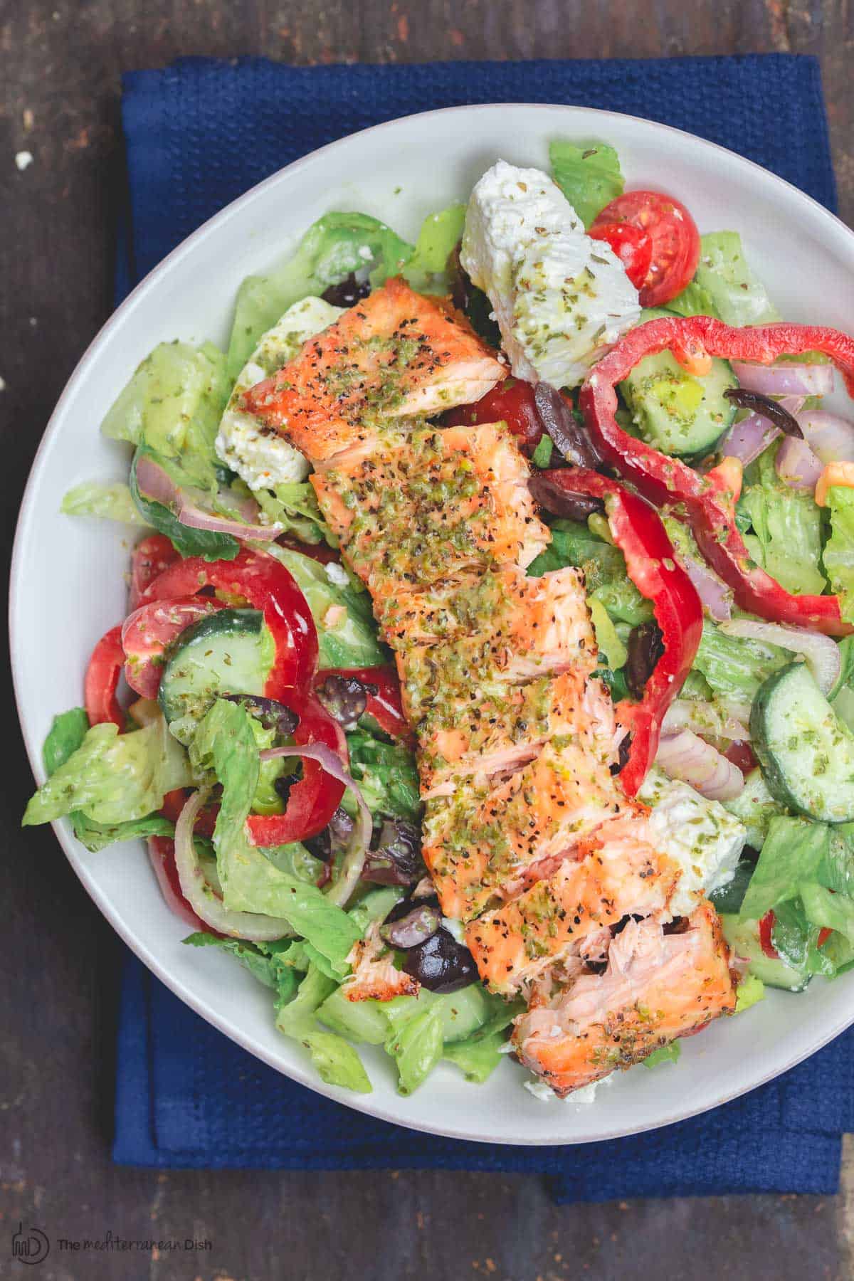 Salmon on top of lettuce, bell peppers, tomatoes and more