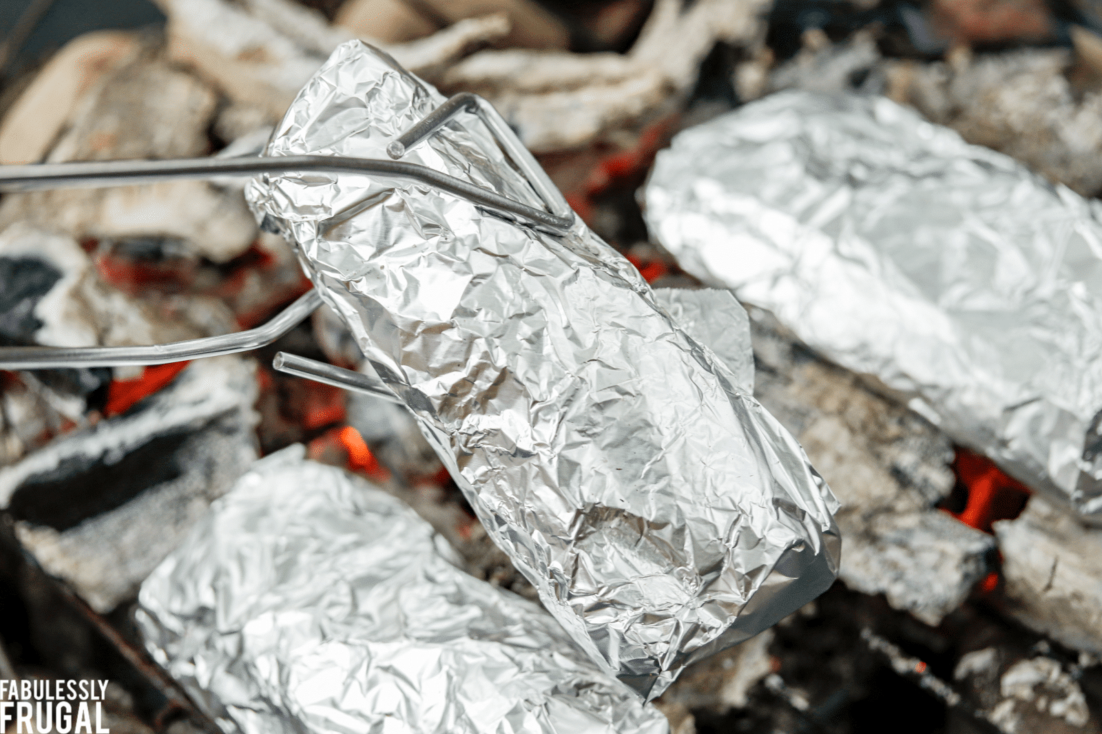 Cooking foil-wrapped burritos on the campfire