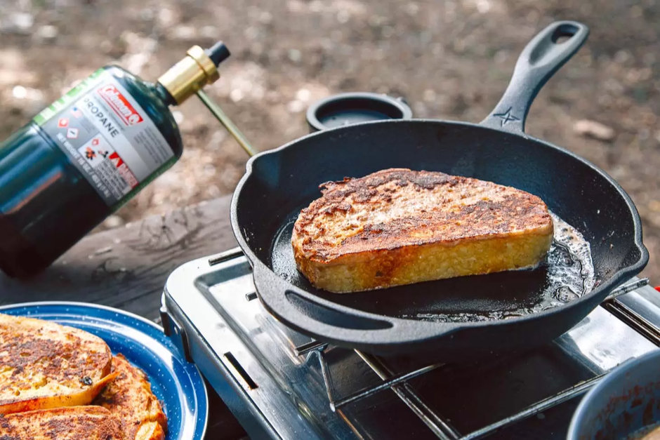 Piece of french toast cooking on a cast iron skillet outdoors
