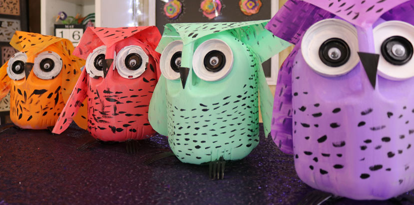 Four different colored owls made from milk jugs