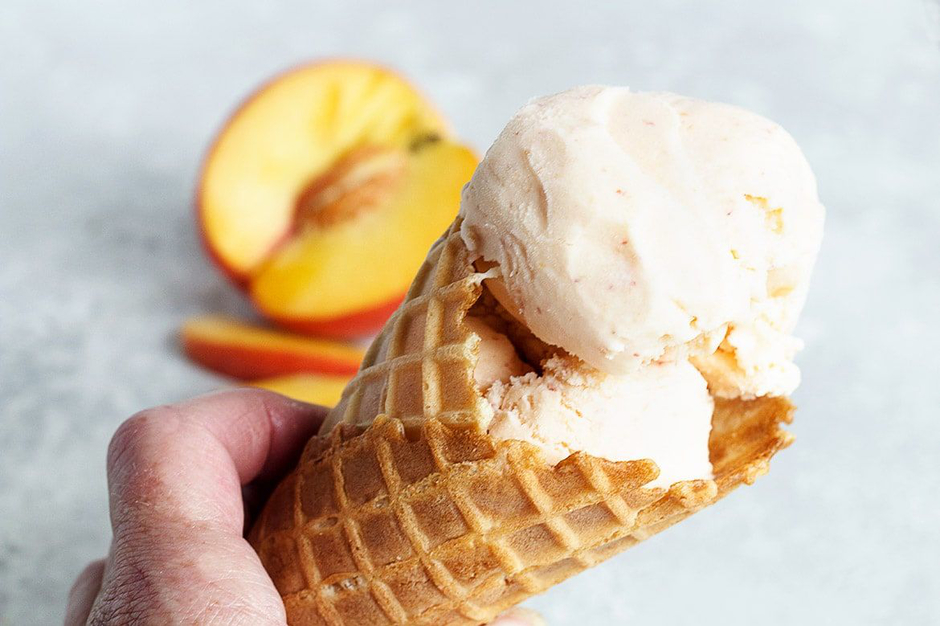 Waffle cone with scoop of peach ice cream