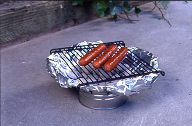 Tin can grill with hot dogs cooking