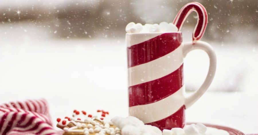 Striped mug of hot cocoa with candy cane poking out