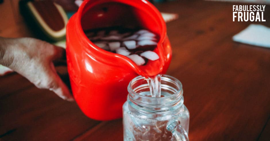 Pouring water from a red jug into a mason jar