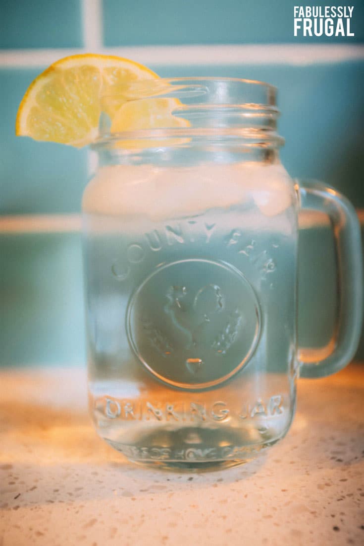 Mason jar full of water with a lemon slice on the rim
