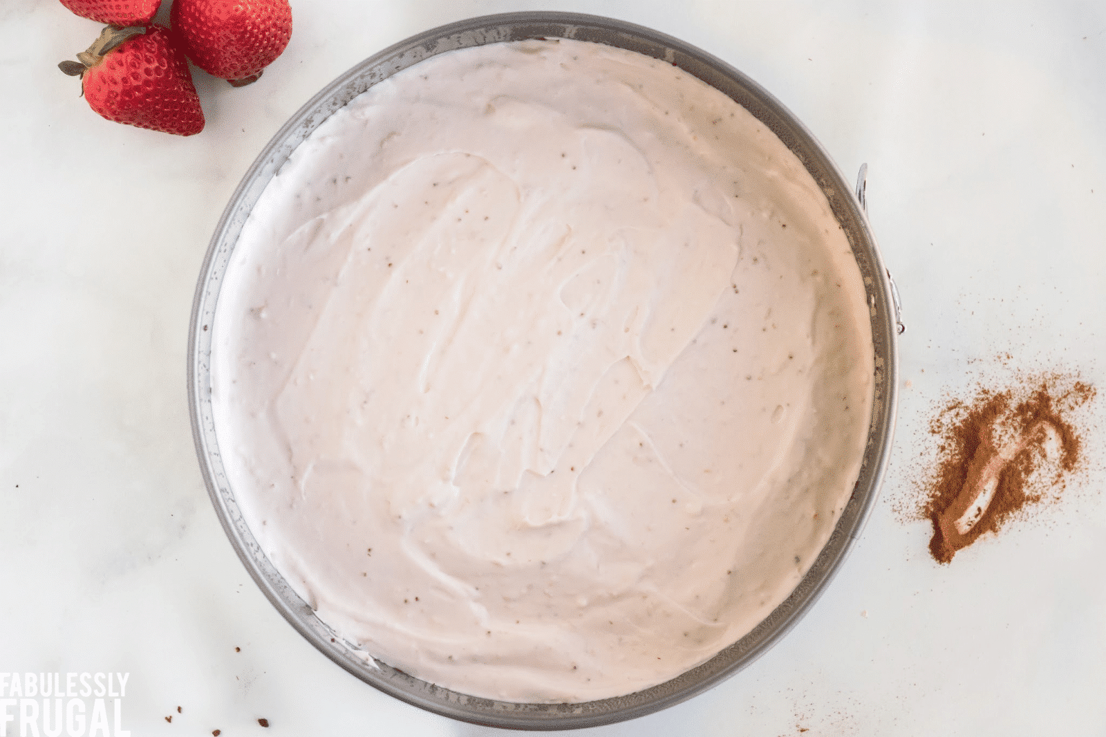 Strawberry cheesecake layer in pan on top of crust