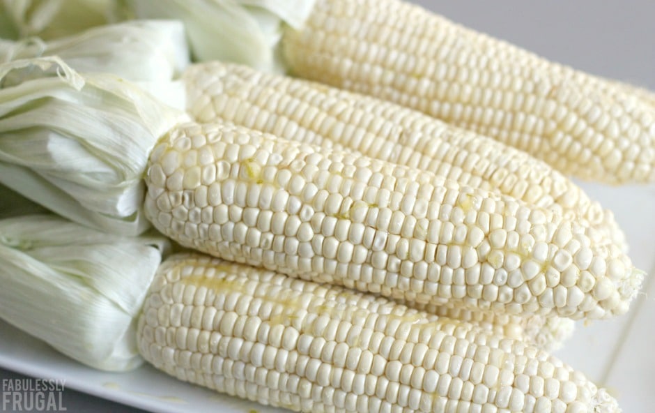 fresh corn on the cob with husks pulled back ready for grilling