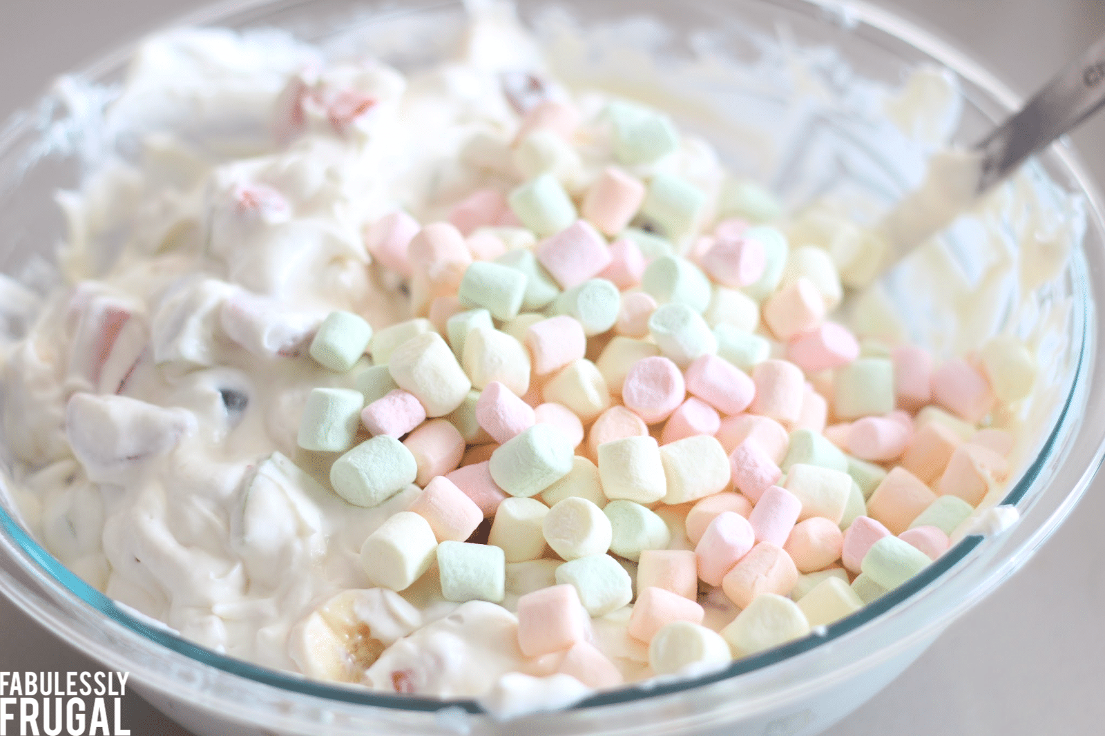 Mixing marshmallows in with fruit salad