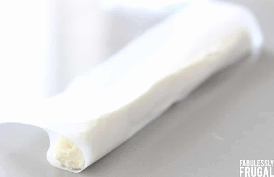 Roll of cream cheese filling with parchment paper around it ready for freezer