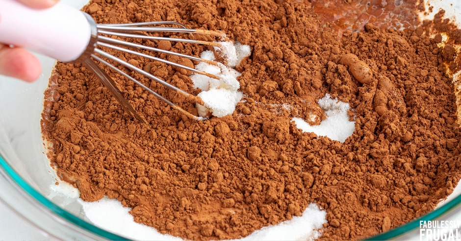 Whisking sugar, coco, eggs, and half and half together in a glass bowl
