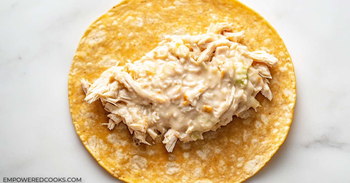 a tortilla with a scoop of chicken and cheese mixture