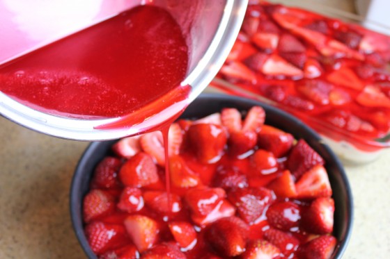 Pouring more gelatin topping over berries