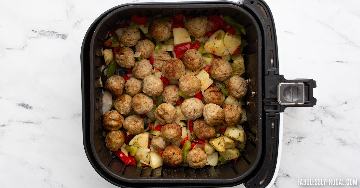 roasted and air fried meatballs, potatoes, onions, and bell peppers in an air fryer basket