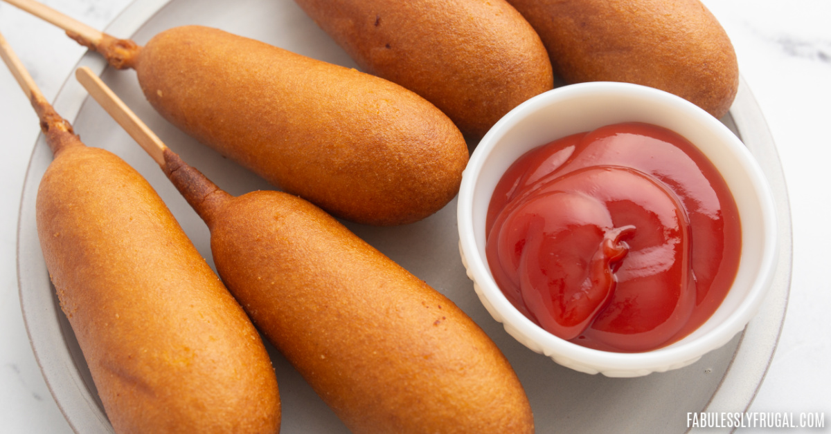 corn dogs on plate with a bowl of ketchup