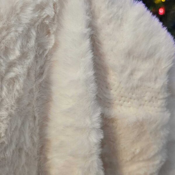 Stacy holding the Naipo faux rabbit fur blanket on the couch